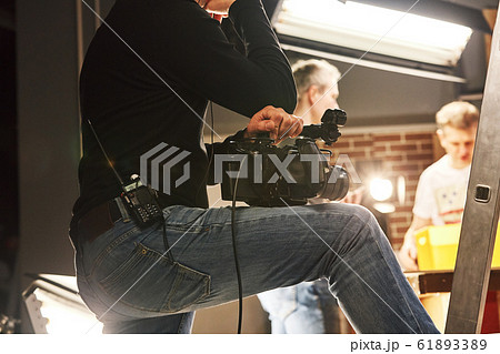 Video production backstage. Behind the scenes of creating video content, a professional team of cameramen with a director filming commercial ads. Video content creation, video creation industry. 61893389