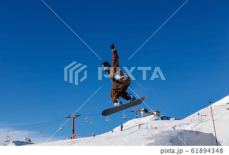 Male snowboarder against the blue sky 61894348