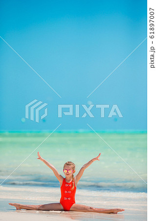 Beautiful little girl doing sporty exercises on the beach 61897007