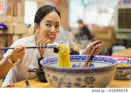 Happy smiling woman eating big bowl of noodle soup in Chinese restaurant. Happy smiling woman eating big bowl of noodle soup in Chinese restaurant. 61899028