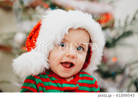 Very cute portrait of little baby boy in Santa hat on Christmas tree lights background bokeh. new year, family, son, toddler child concept. 61899543