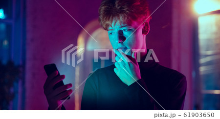 Cinematic portrait of handsome young man in neon lighted interior 61903650