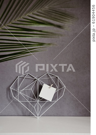 Graceful openwork heart with notes on a concrete wall background. Minimalism. Concept Symbol of love and Valentine's Day. Home Decor Graceful openwork heart with notes on a concrete wall background. Minimalism. Concept Symbol of love and Valentine's Day. Home Decor 61904456