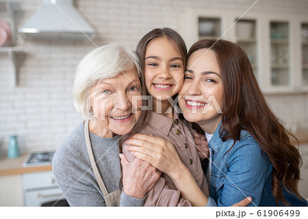 Beautiful and happy woman huggimg her daughter and her mum Beautiful and happy woman huggimg her daughter and her mum 61906499