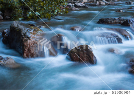 Clear river running fast, hitting rocks. 61906904