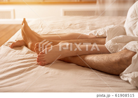 Men's and women's legs stick out from under the blanket. Men's and women's legs stick out from under the blanket. 61908515