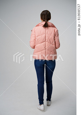 a woman on a white background with her back turned, wearing a pink jacket 61908537