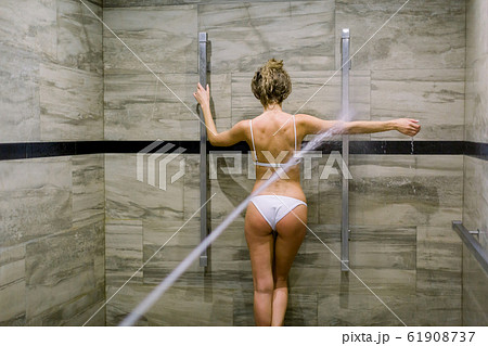 Young woman having water massage treatment in special room for high pressure massage with Sharko shower in spa Young woman having water massage treatment in special room for high pressure massage with Sharko shower in spa 61908737