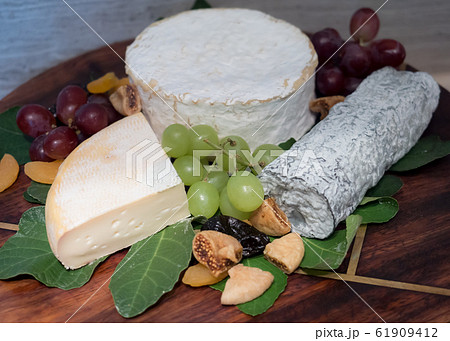 Assortment of tasty and delicious cheese selection  antipasto delicatessen. Reblochon, Brillat Savarin and Sainte Maure de Touraine on wooden board.  61909412