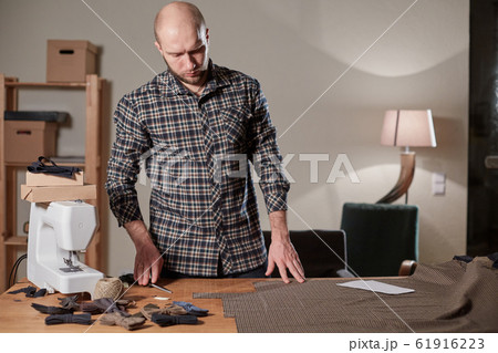 Tailor cutting wool fabric. the line pattern. Craftsman Makes rectangular blanks for Bow ties of woolen fabric. Work with sewing machine in a textile studio. Tailor cutting wool fabric. the line pattern. Craftsman Makes rectangular blanks for Bow ties of woolen fabric. Work with sewing machine in a textile studio. 61916223