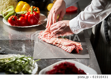 Ribs lamb ready for marinade with rosemary. Cooking with fire in frying pan. Professional chef in a kitchen of restaurant cooking. 61916431