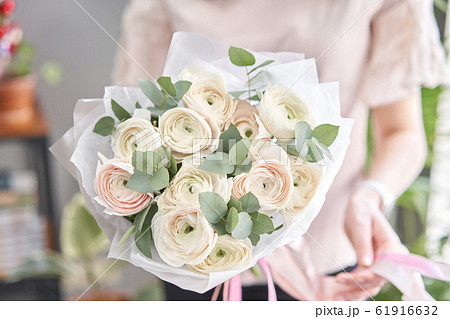 Persian buttercup in womans hands. Bunch pale pink ranunculus flowers with green eucalyptus. The work of the florist at a flower shop Persian buttercup in womans hands. Bunch pale pink ranunculus flowers with green eucalyptus. The work of the florist at a flower shop 61916632