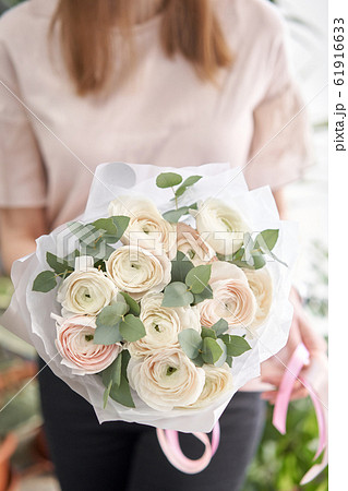 Persian buttercup in womans hands. Bunch pale pink ranunculus flowers with green eucalyptus. The work of the florist at a flower shop Persian buttercup in womans hands. Bunch pale pink ranunculus flowers with green eucalyptus. The work of the florist at a flower shop 61916633