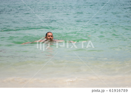 A man swims in the waves of the sea or ocean in a A man swims in the waves of the sea or ocean in a 61916789