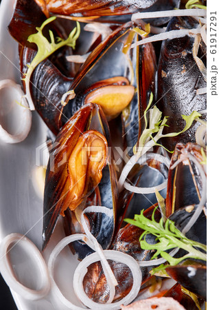 Delicious seafood mussels with arugula and onions. Lemon and baguette . Clams in the shells. Restaurant menu 61917291