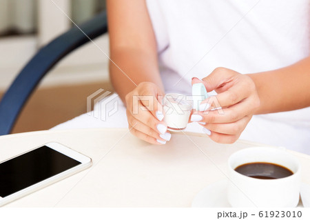 Cropped image of female hands applying cream at 61923010