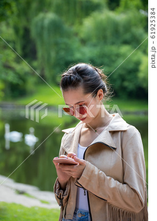 Girl on the street looks at the phone on nature Girl on the street looks at the phone on nature 61925384