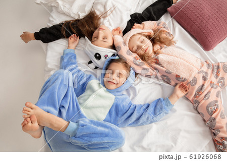 Children in soft warm pajamas having party colored bright playing at home Children in soft warm pajamas having party colored bright playing at home 61926068