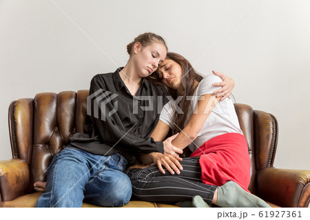Sad Girlfriends Consoling Each Other Hugging on Love Seat 61927361