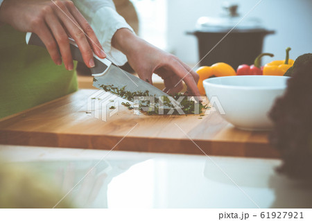 Unknown human hands cooking in kitchen. Woman is busy with vegetable salad. Healthy meal, and vegetarian food concept Unknown human hands cooking in kitchen. Woman is busy with vegetable salad. Healthy meal, and vegetarian food concept 61927921