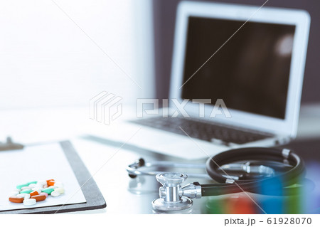 Stethoscope, prescription medical form lying on glass table with laptop computer. Medicine or pharmacy concept. Medical tools at doctor working table Stethoscope, prescription medical form lying on glass table with laptop computer. Medicine or pharmacy concept. Medical tools at doctor working table 61928070