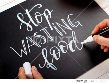 Woman writing on a chalkboard Stop wasting food Woman writing on a chalkboard Stop wasting food 61930590