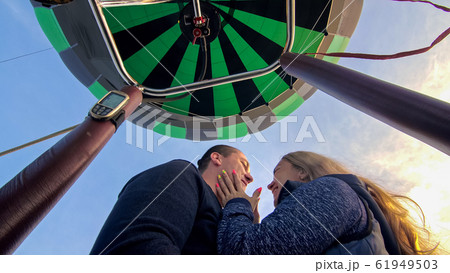 Adventure love couple on hot air balloon watermelon. Man and woman kiss hug love each other. Burner directing flame into envelope. Happy people. 61949503