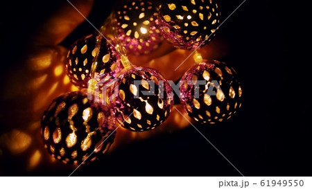 Magic lanterns spin and give beautiful glare to the walls. New Year glowing balls with led diodes are held in hands. Warm lamp light christmas mood. 61949550