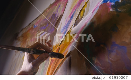 Artist designer draws an eagle on the wall. Craftsman decorator paints a picture with acrylic oil color brush. Close-up dark magic cinematic look. 61950007