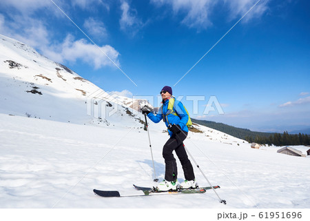 Skier tourist with backpack on background of bright blue sky and beautiful mountain panorama. 61951696