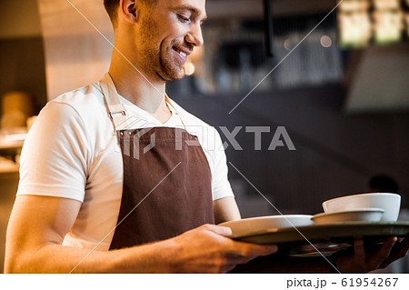 Caucasian happy waiter waiting for order near the kitchen Caucasian happy waiter waiting for order near the kitchen 61954267