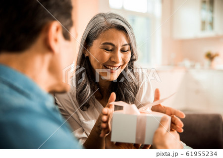 Happy attractive lady looking at present while taking it 61955234