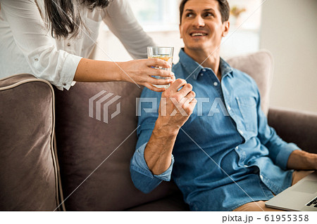 Smiling man taking glass of water from his wife 61955358