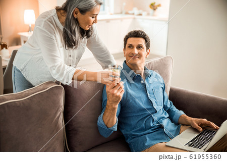 Smiling adult man taking glass of water from lady Smiling adult man taking glass of water from lady 61955360