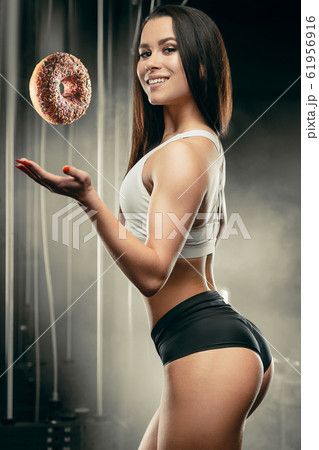 Fitness woman with donut at workout in the gym Fitness woman with donut at workout in the gym 61956916