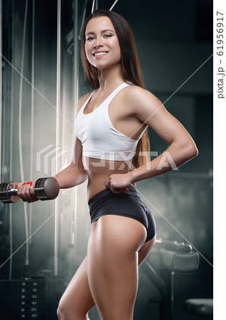 Fitness woman pumping up arm muscles in the gym 61956917