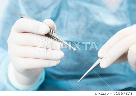 Surgeon holding a surgical needle holder with silk Surgeon holding a surgical needle holder with silk 61967873
