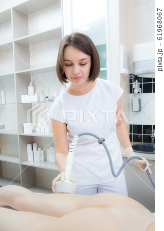 The cosmetologist reduces cellulite on the The cosmetologist reduces cellulite on the 61968067