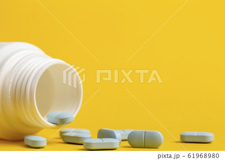Medicine bottle and blue pills scattered around Medicine bottle and blue pills scattered around 61968980
