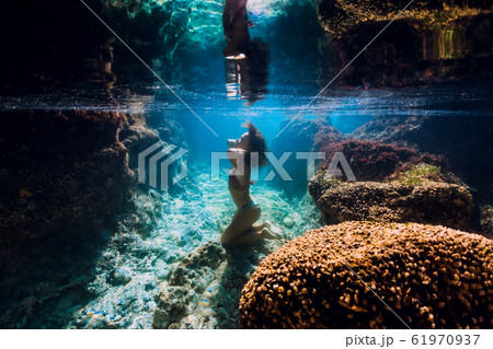 Woman in bikini posing underwater near corals in blue ocean. 61970937