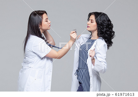 Female doctor examining another woman with stethoscope Female doctor examining another woman with stethoscope 61971613