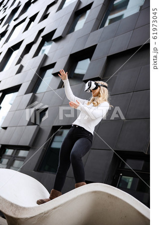 Young Woman Wearing Virtual Reality Glasses In Front Of Futuristic Building Young Woman Wearing Virtual Reality Glasses In Front Of Futuristic Building 61973045