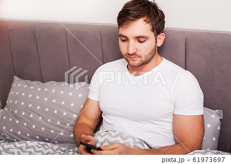 Man addicted to his mobile phone in bed 61973697