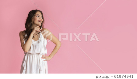 Beautiful girl in dress looking at copy space on pink background 61974941