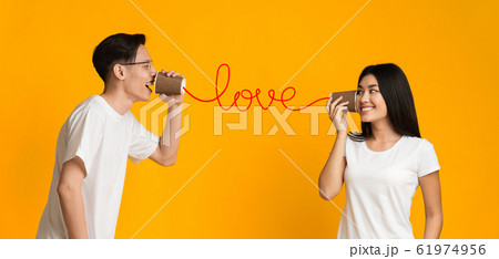 Asian couple sharing feelings through can phone Asian couple sharing feelings through can phone 61974956