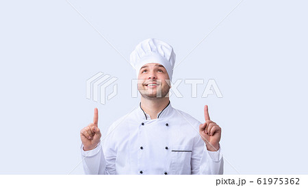 Chef Guy Pointing Fingers Upward Standing Over White Background, Panorama Chef Guy Pointing Fingers Upward Standing Over White Background, Panorama 61975362