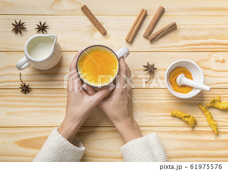 Female drinking turmeric latte of golden milk with cinnamon 61975576