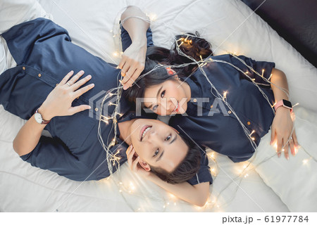 Asian couple in love lying on the bed with fairy light Asian couple in love lying on the bed with fairy light 61977784