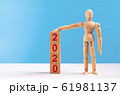 Wooden mannequin figure raise a hand and put on tower of cubes with red inscription 2020 year 61981137