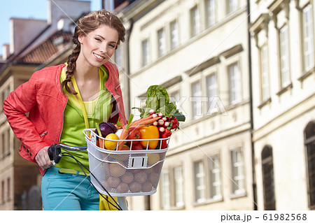 Pretty young woman with bicycle and groceries in Pretty young woman with bicycle and groceries in 61982568